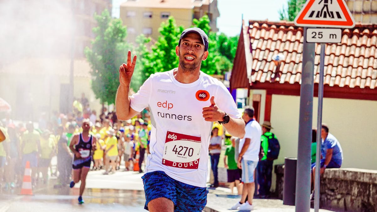 A joyful runner flashes a peace sign and thumbs up during a sunny marathon in the city.